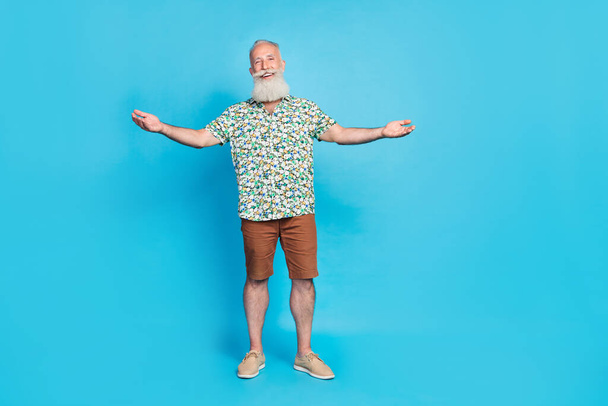 Full size portret van positieve oude man handen nodigen u uit geïsoleerd op blauwe kleur achtergrond. - Foto, afbeelding