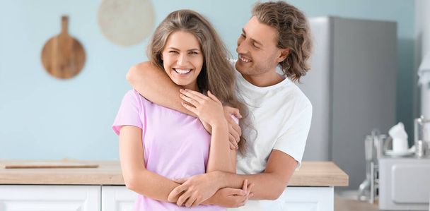 Happy young couple in pajamas hugging in kitchen - Photo, Image