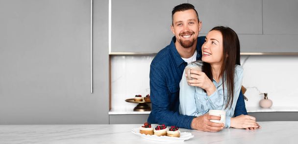 Glückliches junges Paar trinkt zu Hause Tee mit Kuchen - Foto, Bild