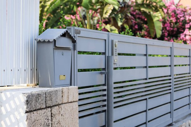 Вид на металлический почтовый ящик возле забора на открытом воздухе - Фото, изображение