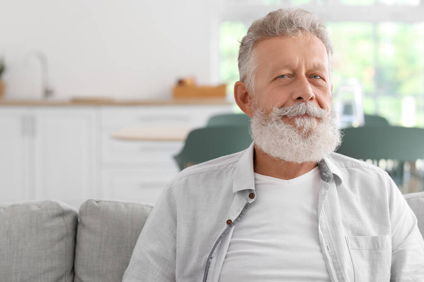 Starszy brodaty mężczyzna siedzi na kanapie w kuchni, zbliżenie - Zdjęcie, obraz