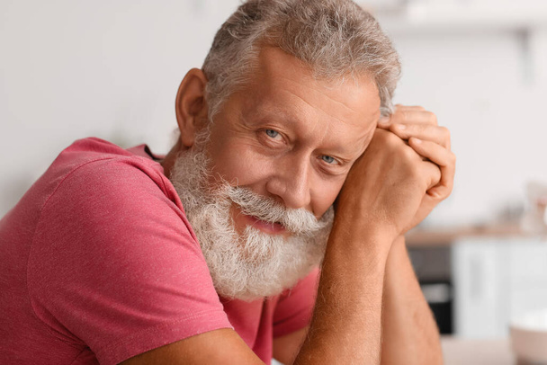 Senior bearded man smiling in kitchen, closeup - Fotó, kép