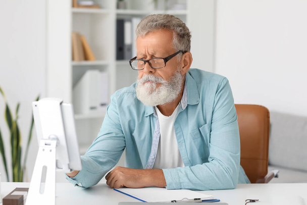 Senior bearded man using tablet computer at table in office - Photo, image