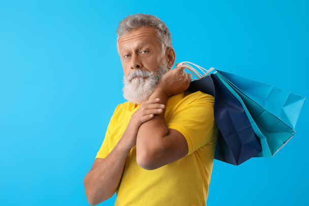 Ανώτερος άνθρωπος με τσάντες ψώνια σε μπλε φόντο - Φωτογραφία, εικόνα