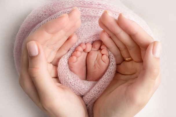 Childrens legs in the hands of mother, father, parents. Feet of a tiny newborn close up. Mom and her child. Happy family concept. Beautiful concept image of motherhood stock photo. - Foto, Imagen