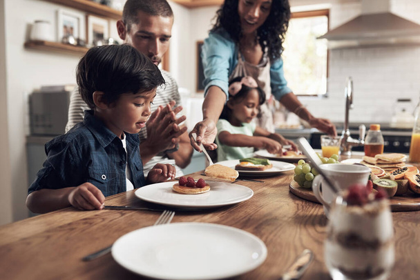 Cucinare e 'la mia terapia. un ragazzino sorridente a tavola con la sua famiglia sullo sfondo - Foto, immagini