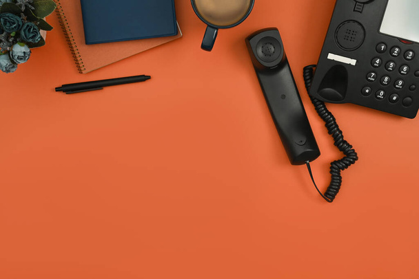 Obere Ansicht von Notizblock, Kaffee und Telefon auf orangefarbenem Hintergrund. Flache Lage, Draufsicht mit Kopierraum. - Foto, Bild