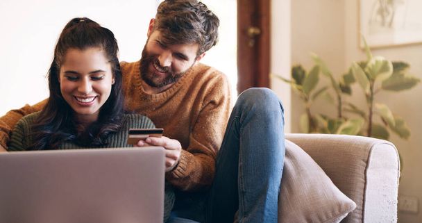 Shopping sprees from the comfort of home. a young couple using a laptop and credit card on the sofa at home - Фото, зображення