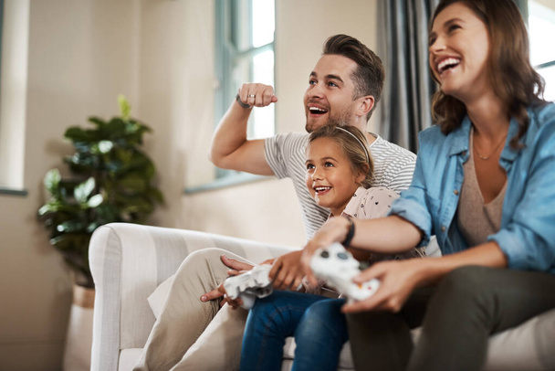 Cuando pasas tiempo con la familia ya eres un ganador. una familia joven y feliz jugando videojuegos en el sofá en casa - Foto, imagen