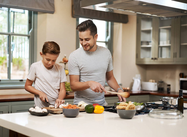 Jsi připravená s těmi houbami. mladý chlapec pomáhá svému otci vařit v kuchyni - Fotografie, Obrázek