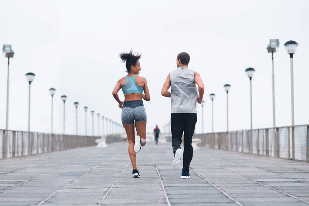 Wyścig jest na ich cele fitness. Zdjęcie z tyłu dwóch młodych sportowców ćwiczących razem na świeżym powietrzu - Zdjęcie, obraz