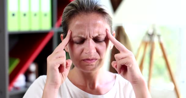 Genç bir kadının portresi gözlerini kapattı tapınaklara dokundu ve acıdan acı çekti. Yüksek tansiyonu olan bir kadın baş ağrısı ve sağlıksız stres migreni. - Video, Çekim