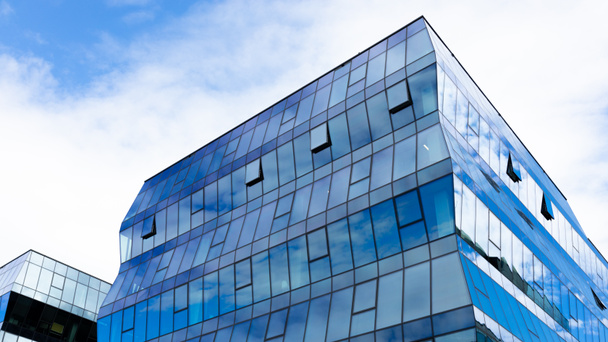 Modern office building with glass facade on a sky background. Transparent glass wall of office building. - Foto, afbeelding
