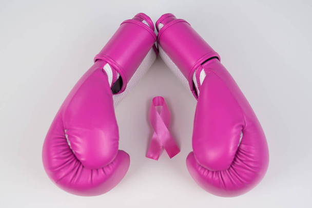 Pink boxing gloves and a pink silk ribbon on a white background. Breast cancer concept - Фото, изображение