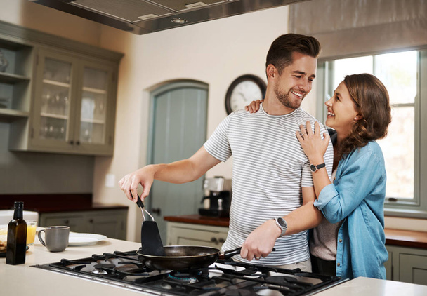 What did I do to deserve such a perfect partner. a young woman embracing her partner while he cooks breakfast - Foto, immagini