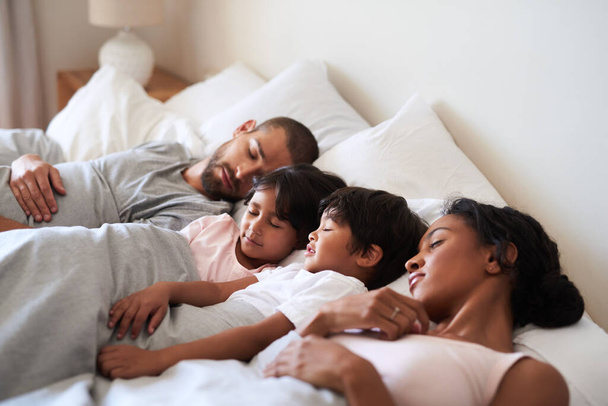 Everyone is getting some much needed rest. a beautiful young family of four fast asleep in bed together in their bedroom at home - Fotoğraf, Görsel