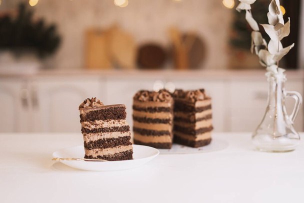 Pezzo di torta al cioccolato su piatto rotondo con forchetta davanti alla cucina. - Foto, immagini
