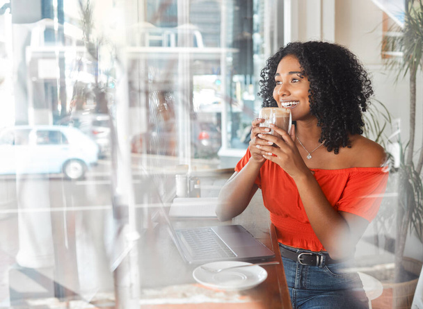 Coffee shop, thinking and happy black woman in cafe drinking espresso or cappuccino while doing remote work on laptop. Freelance female with drink for motivation, idea and wifi for blog in London. - Foto, Bild