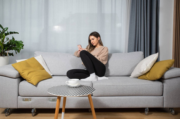 Happy young woman caller talking on the phone at home, cheerful teen girl enjoys pleasant mobile conversation, smiling millennial female holding cell speaking making call by telephone in living room - Фото, изображение