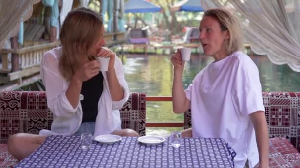 Két fiatal turista kávét iszik egy törökországi kávézóban. Barátok szórakozás beszélgetni egy kirándulás Alanya, Törökország. - Felvétel, videó