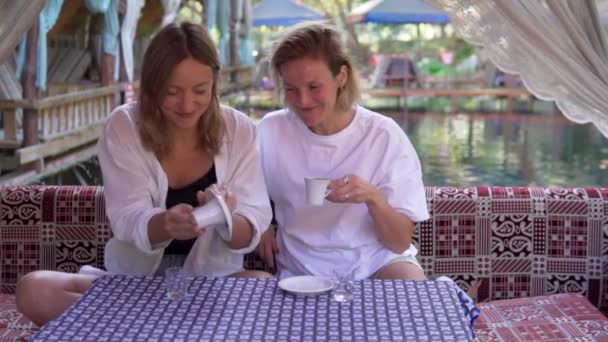 Dwie młode turystki piją kawę w kawiarni w Turcji. Podróżujące kobiety przepowiadające przyszłość na tureckiej kawie w restauracji - Materiał filmowy, wideo