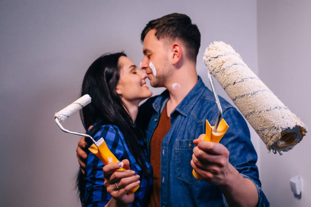 Couple heureux embrassant après rénovation leur nouvelle maison avec rouleau de peinture. - Photo, image