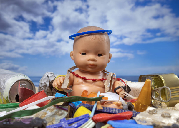 Uma boneca cercada por lixo e lixo em uma bela praia  - Foto, Imagem
