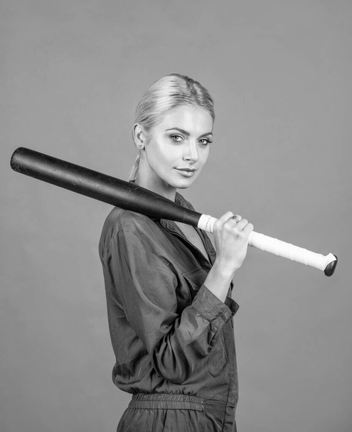 woman in uniform hold baseball or cricket bat sport game equipment on orange background, cricket. - 写真・画像