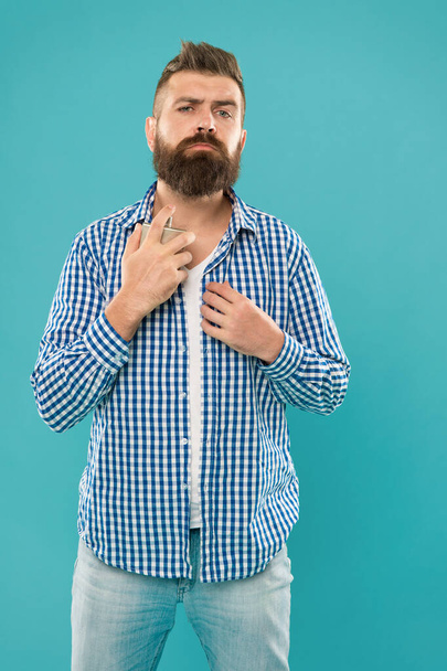 charismatic bearded man in casual checkered shirt hold male perfume bottle on blue background, fragrance. - Fotografie, Obrázek
