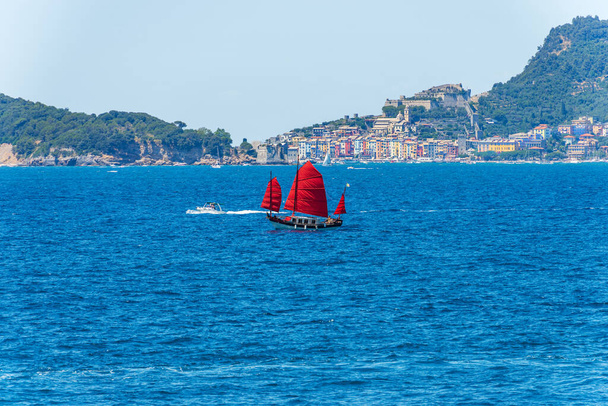 Vieux voilier avec trois voiles rouges dans la mer Méditerranée bleue en face de la célèbre ville de Porto Venere ou Portovenere, patrimoine mondial de l'UNESCO, golfe de La Spezia, Ligurie, Italie, Europe. - Photo, image
