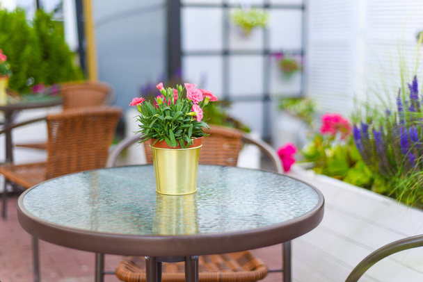 テーブルと椅子付きのカフェで設定された家具花の花束と屋外. - 写真・画像
