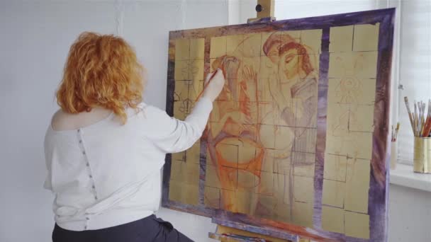 Artiste peintre caucasienne dessin avec pinceau sur toile dans atelier atelier intérieur. Création peinture créative. Jeune femme artiste peinture tableau sur toile en atelier d'art. Vidéo 4k - Séquence, vidéo