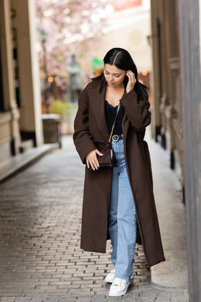 teljes hossza barna nő divatos kabát test rögzítő haj az utcán Prágában - Fotó, kép