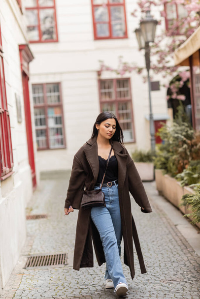 young and pretty woman in trendy autumn clothes walking along narrow street in prague - Fotografie, Obrázek