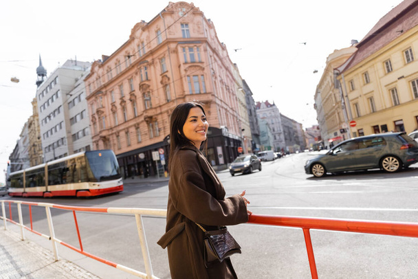 Happy traveler in coat standing near road on street in Prague  - Фото, зображення