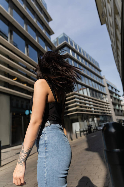 Visszapillantás a tetovált nőre, aki Prága elmosódott városi utcáján áll  - Fotó, kép