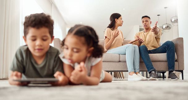 Mother, father and disagreement on living room sofa while children are playing with tablet on the floor at home. Mama and dad fighting, argue or conflict in difficult situation on couch in dispute. - Photo, Image