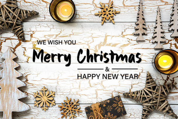 キャンドル、木や雪の結晶、星や贈り物のようなクリスマスの装飾と白い木製のヴィンテージクリスマスの背景。英語のテキストメリークリスマスとハッピーニューイヤーと素朴なカード - 写真・画像