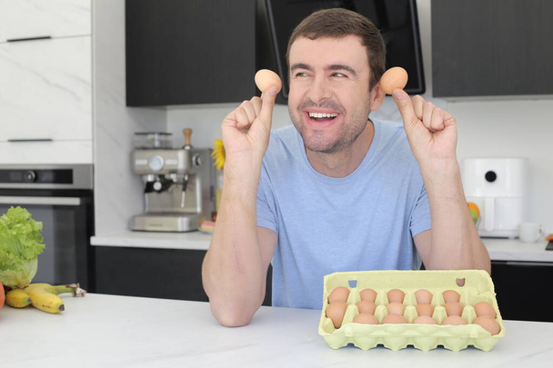 portrait of handsome young man holding eggs at kitchen - Photo, image