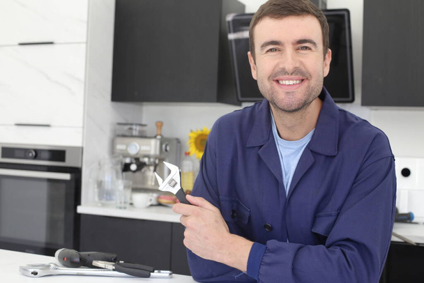 portrait of handsome young man repairman in uniform at kitchen - Photo, Image