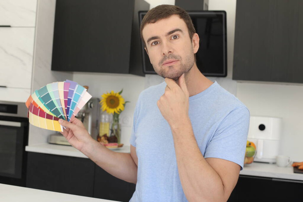 portrait of handsome young man with color samples for renovation at kitchen - Photo, Image