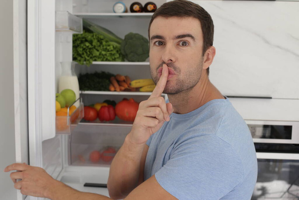 портрет красивого молодого чоловіка перед відкритим холодильником на кухні
 - Фото, зображення