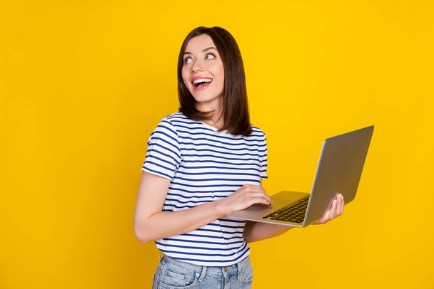 Photo portrait of cute young woman hold laptop look empty space director dressed trendy striped clothes isolated on yellow color background. - Foto, imagen