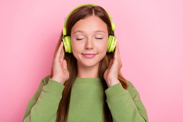 Photo of dreamy sweet schoolgirl wear green sweatshirt arms earphones closed eyes isolated pink color background. - Foto, Imagem