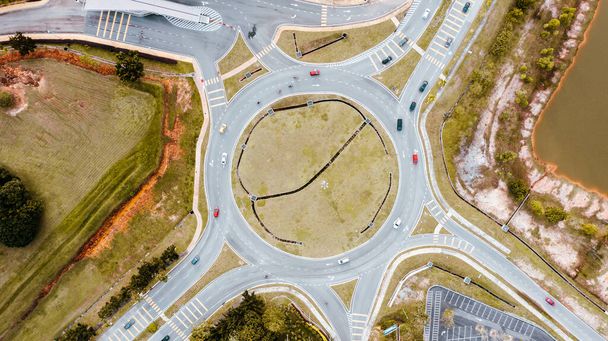 Aerial top down view of traffic roundabout on a main road. Aerial view of roundabout in the city in the summer. Aerial view of traffic infrastructure. Sedan cars moving over the asphalt. Road crossing - Photo, Image