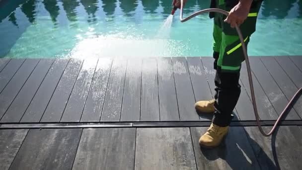 Mann reinigt Pooldeck mit Gartenschlauch - Filmmaterial, Video