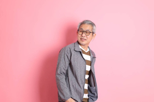 The 40s adult Asian man stnading on the pink background with casual clothes. - Фото, изображение