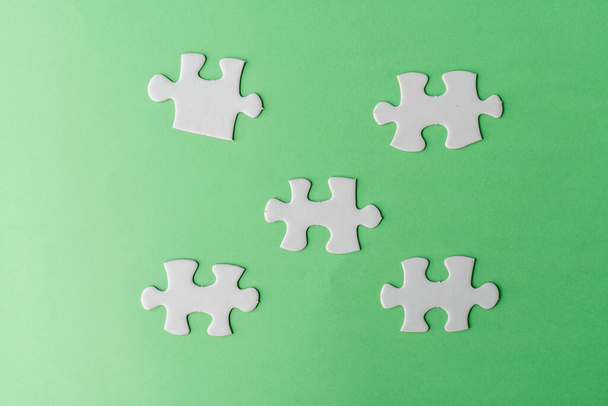Pieces of white jigsaw puzzle on green background - Photo, Image