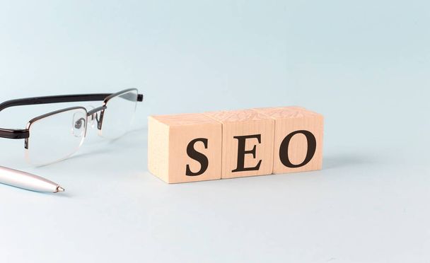 Text SEO -Search Engine Optimization- written on the wooden cubes on a blue background - Photo, Image
