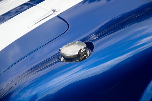 Χρωματισμένο καπάκι αερίου σε ένα λευκό και μπλε σπορ αυτοκίνητο οριζόντια - Φωτογραφία, εικόνα